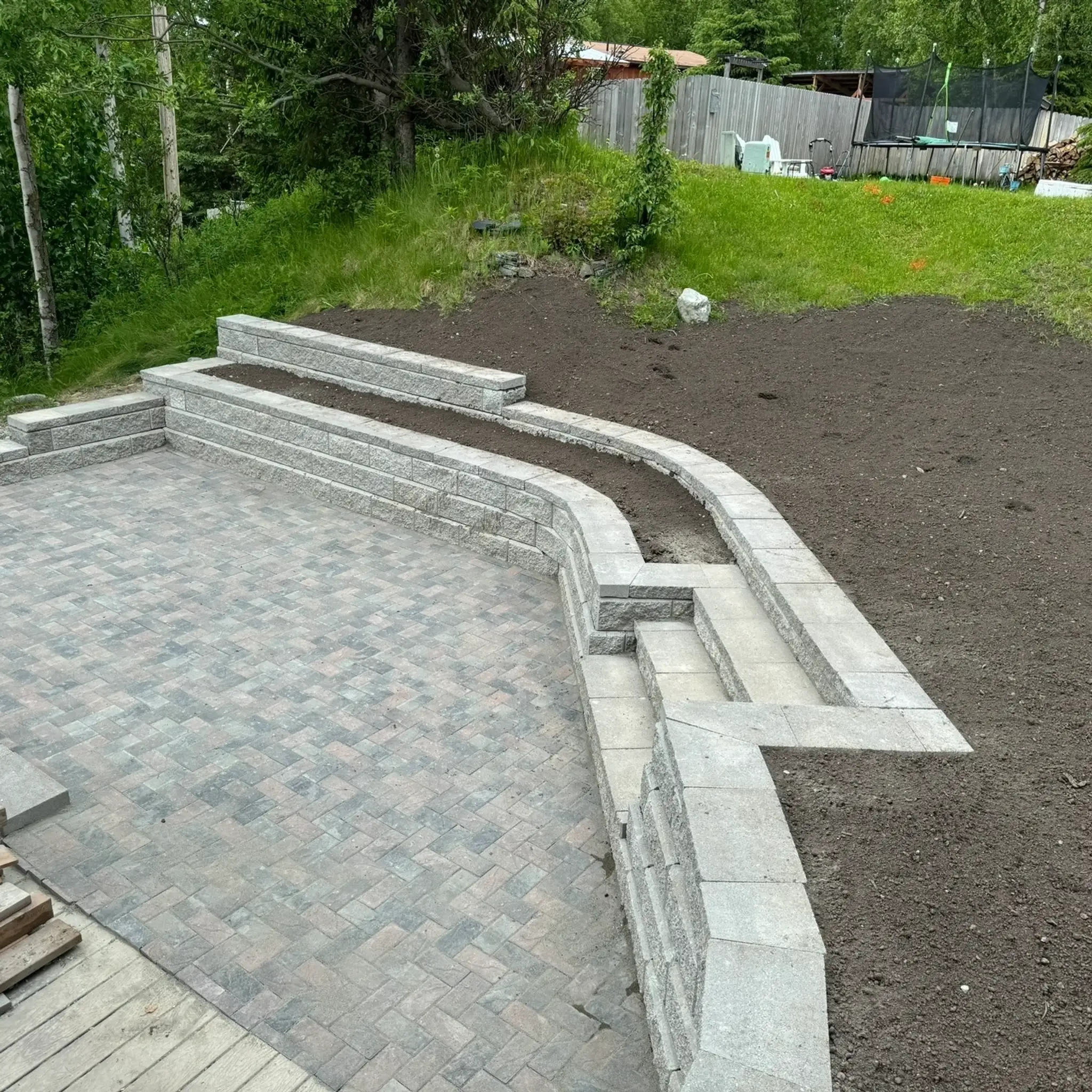 Block retaining wall and steps enclosing a herringbone paver patio