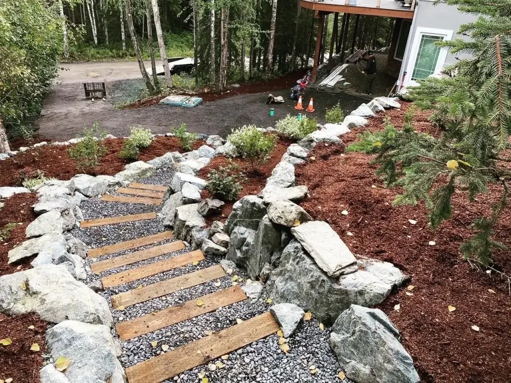 Timber and gravel steps set between boulder edging and mulched planting beds